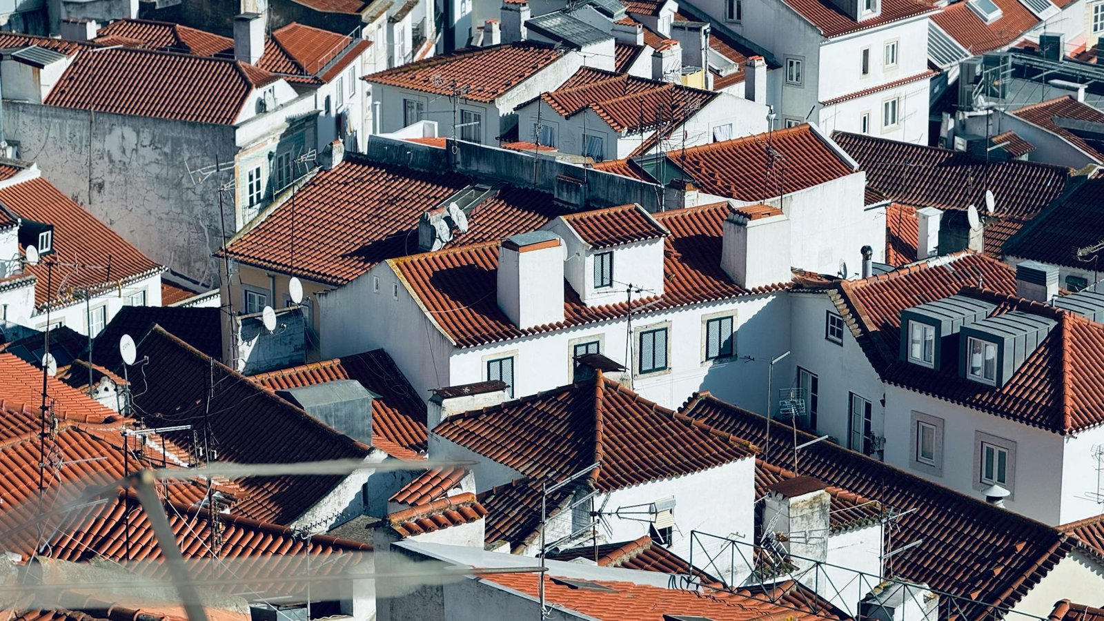 Explore the picturesque red rooftops of Lisbon, Portugal, under clear sunlight.